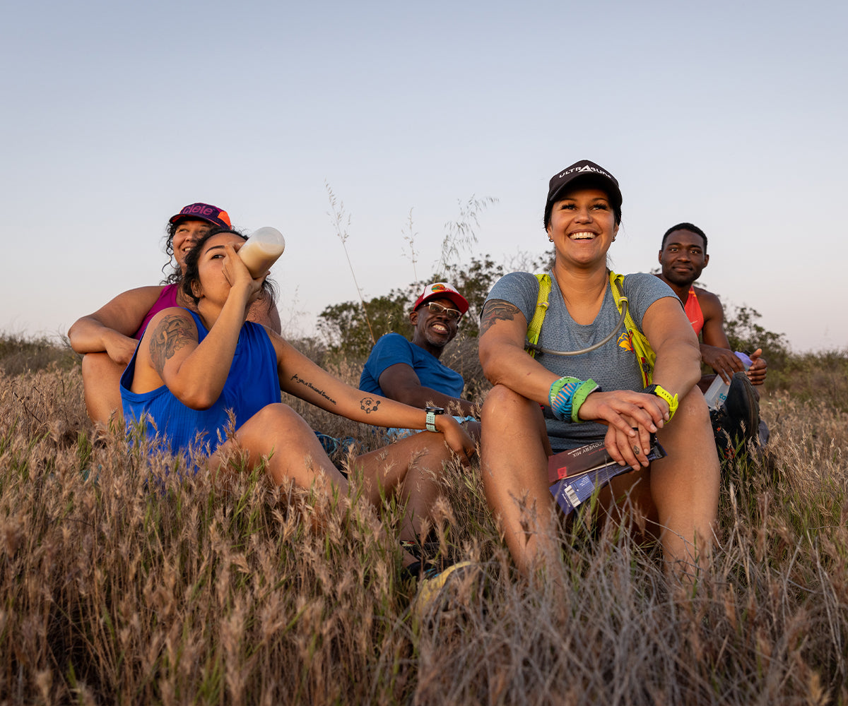 Five runners sitting in the grass outside